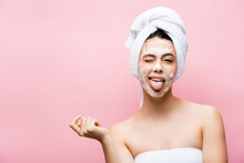 Beautiful Woman With Towel On Hair And Foam On Face Showing Tongue Isolated On Pink