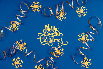 Wall Mural - Holiday background with Merry Christmas wording, golden snowflakes, and ribbons on classic blue. Holiday celebration card concept