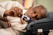 Selective Focus On Thermometer, Sick Bed Ridden Old Man Seeing Temperature On Thermometer.