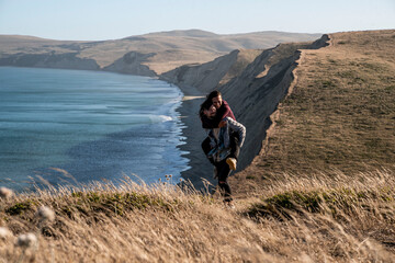 young couple piggy back ride along the coast of california 