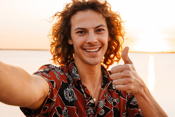 Happy young man taking a selfie while standing