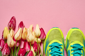 Pair of sport shoes and tulip flowers on pink pastel background, copy space. New sneakers. Overhead shot of running footwear. Top view, flat lay. Spring, sport, minimal concept