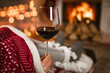 © Mediteraneo - Woman drinking wine from glass sitting and relaxation near fireplace and christmas tree.