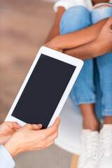 Wall Mural - Cropped view of psychologist with digital tablet near blurred african american girl on background