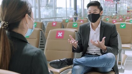 Wall Mural - New normal and social distancing concept.Businessman and businesswoman wearing face mask meeting during airline flight status and sitting with distance during coronavirus 2019 outbreak at airport