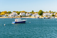 Empty Boat Moored Off  A Coast Lined With Residential Buildings With Private Wooden Jetties On A Clear Autumn Day. Hyannis, Cape Cod, MA, USA.