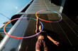 © VISTA by Westend61 - Sporty woman juggling plastic hoops outside modern building in city