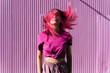 © VISTA by Westend61 - Young woman with dyed red hair dancing in front of purple wall in the city