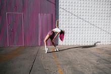 Young Woman With Dyed Red Hair Dancing In Front Of Purple Wall In The City