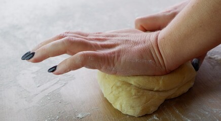Making homemade dough by female hands on wooden table background. Cooking concept.