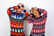 © Roquillo - Young couple wearing Christmas sweater standing against white wall suffering from strong headache desperate and stressed because of overwork. Depression and pain concept.