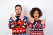 © Roquillo - Young couple wearing Christmas sweater standing against white wall has rejection expression crossing arms and palms doing negative sign, angry face.