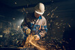 Locksmith in special clothes and goggles works in production. Metal processing with angle grinder. Sparks in metalworking