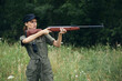© SHOTPRIME STUDIO - Woman soldier with a gun in hand takes aim green overalls green trees