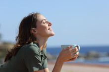 Happy Woman Holding Coffee Mug Breaths On The Beach