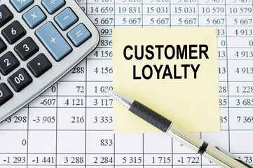 Customer loyalty card text on the on yellow paper on the table, near a calculator, pen and financial statements