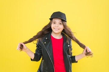 Wall Mural - Happy small girl child with beauty look in casual fashion style hold long brunette hair yellow background, haircare