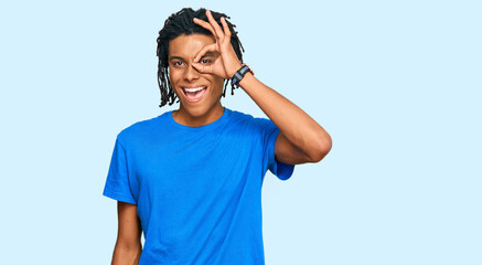 Young african american man wearing casual clothes doing ok gesture with hand smiling, eye looking through fingers with happy face.