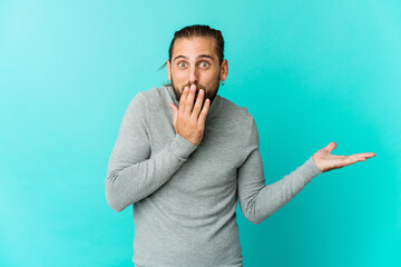 Young man with long hair look impressed holding copy space on palm.