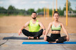 © Georgii - Young couple in stylish sportswear do yoga outside, pair training, healthy lifestyle habit