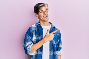 Young hispanic man wearing casual clothes cheerful with a smile of face pointing with hand and finger up to the side with happy and natural expression on face