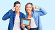 © Krakenimages.com - Couple of women holding empty frame smiling pointing to head with one finger, great idea or thought, good memory