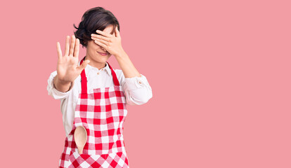 Sticker - Beautiful young woman with short hair wearing professional cook apron covering eyes with hands and doing stop gesture with sad and fear expression. embarrassed and negative concept.