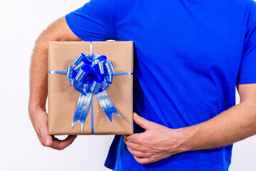 Hands close-up. A courier in a blue uniform is holding a gift box with a bow. Happy New year and merry Christmas. Secure contactless remote delivery of holiday gifts during coronavirus