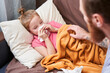© Yakobchuk Olena - Father sitting near his sick daughter wiping her nose