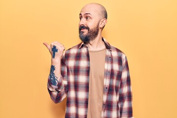 Canvas Print - Young handsome man wearing casual clothes smiling with happy face looking and pointing to the side with thumb up.