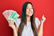 © Krakenimages.com - Young brunette woman holding norwegian krone banknotes screaming proud, celebrating victory and success very excited with raised arm