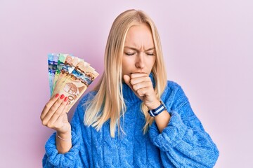 Sticker - Young blonde girl holding canadian dollars feeling unwell and coughing as symptom for cold or bronchitis. health care concept.