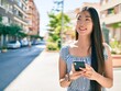 © Krakenimages.com - Young chinese woman smiling happy using smartphone at street of city.