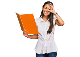 Canvas Print - Beautiful hispanic woman reading book smiling happy doing ok sign with hand on eye looking through fingers