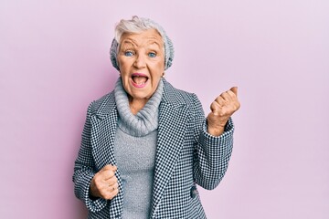Senior grey-haired woman wearing wool winter sweater celebrating surprised and amazed for success with arms raised and eyes closed