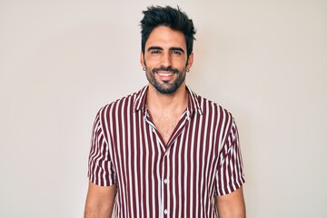 Handsome hispanic man with beard wearing casual clothes looking positive and happy standing and smiling with a confident smile showing teeth