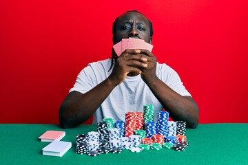 Poster - Handsome young black man playing gambling poker covering face with cards looking at the camera blowing a kiss being lovely and sexy. love expression.