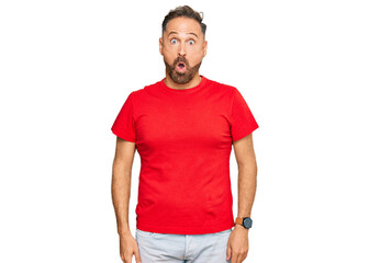 Poster - Handsome middle age man wearing casual red tshirt afraid and shocked with surprise expression, fear and excited face.