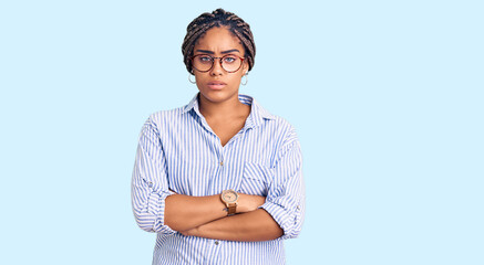 Sticker - Young african american woman with braids wearing casual clothes and glasses skeptic and nervous, disapproving expression on face with crossed arms. negative person.