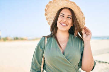 Wall Mural - Young hispanic woman on vacation smiling happy walking at the beach