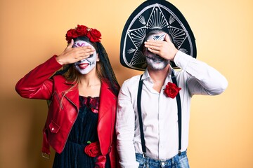 Poster - Couple wearing day of the dead costume over yellow smiling and laughing with hand on face covering eyes for surprise. blind concept.