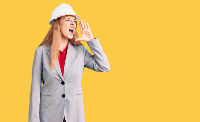 Canvas Print - Beautiful young woman wearing architect hardhat shouting and screaming loud to side with hand on mouth. communication concept.