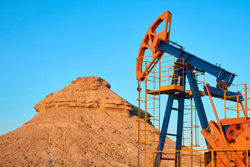 Wall Mural - Oil pump are working in the blue sky background. 
World Oil Industry. Western region of Kazakhstan.

A oil pump is the overground drive for a reciprocating piston pump in an oil well.