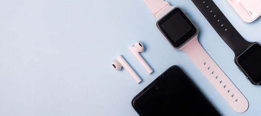 The layout of the watch and the phone on a blue background. Appliances and electronics. Modern gadgets. Phone headphones watch. Business. Wireless headphone. Watch with pedometer.