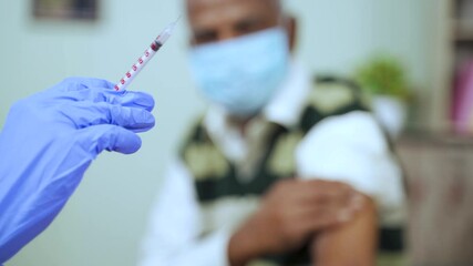 Wall Mural - Close up of selective focus of Doctor holding syringe or injection after making a vaccination shot in the shoulder of patient at home - concept of home health check