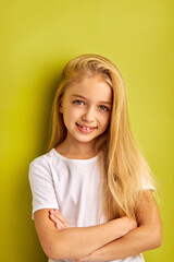 Wall Mural - happy kid girl with long hair smiles at camera isolated on green background, people, children concept, human emotions