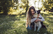 Beautiful woman with playful dog on fresh green meadow