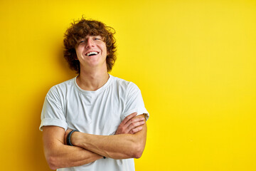 portrait of happy curly young man isolated over yellow studio background, handsome guy shine with happiness, has perfect toothy smile