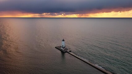 Wall Mural - Beautiful sunset aerial rising high up above the white colored Ludington breakwater lighthouse with blue and orange sky and clouds above reflecting on the calm water of Lake Michigan below.