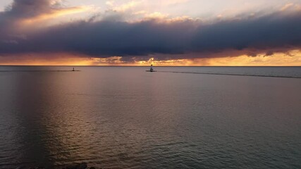 Wall Mural - beautiful sunset aerial panning in over a pier towards the white colored ludington breakwater lighth